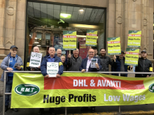 Strikers with placards and an RMT banner reading "DHL & Avanti: Huge Profits, Low Wages"