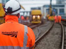Photograph of a Network Rail worker in orange hi-vis clothing and white hard hat